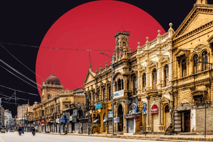 A street view of historic, ornate sandstone buildings with an HBL and Bata sign, set against a dark sky featuring a massive, solid red circle. its saddar market of karachi