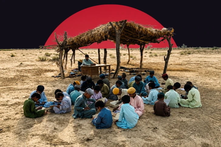 An outdoor makeshift school in a dry, rural area where a group of children sit on the dirt ground studying under a rudimentary thatched-roof shelter supported by wooden posts, with a teacher seated at a desk. The scene is set against a dark background featuring a massive, solid red circle rising behind the structure.