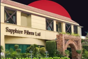 The exterior facade of the Sapphire Fibers Ltd building featuring beige walls, dark-framed windows, and a brick archway entrance, set against a dark background with a large red circle.