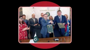 Government officials shaking hands and holding signed bilateral folders during a formal signing ceremony, set against a dark background with a red circle